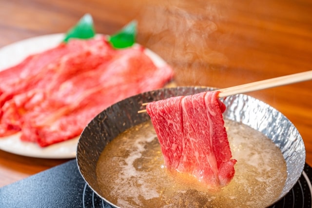 しゃぶしゃぶ用の肉を、箸で鍋に入れる画像